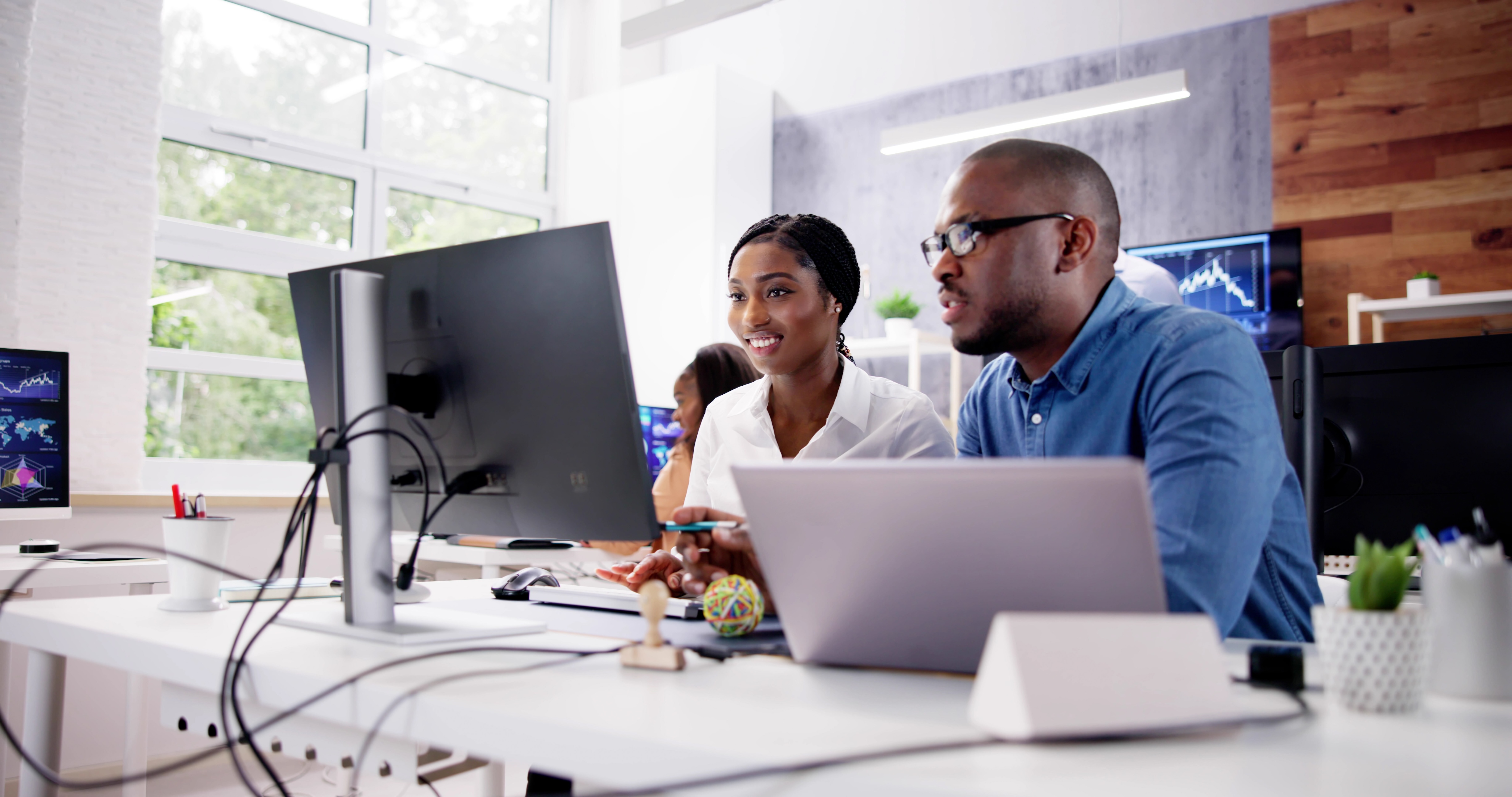 Photo of a man and a woman working together at a computer to illustrate how real-time alerts streamline processes and build trust between security teams and developers