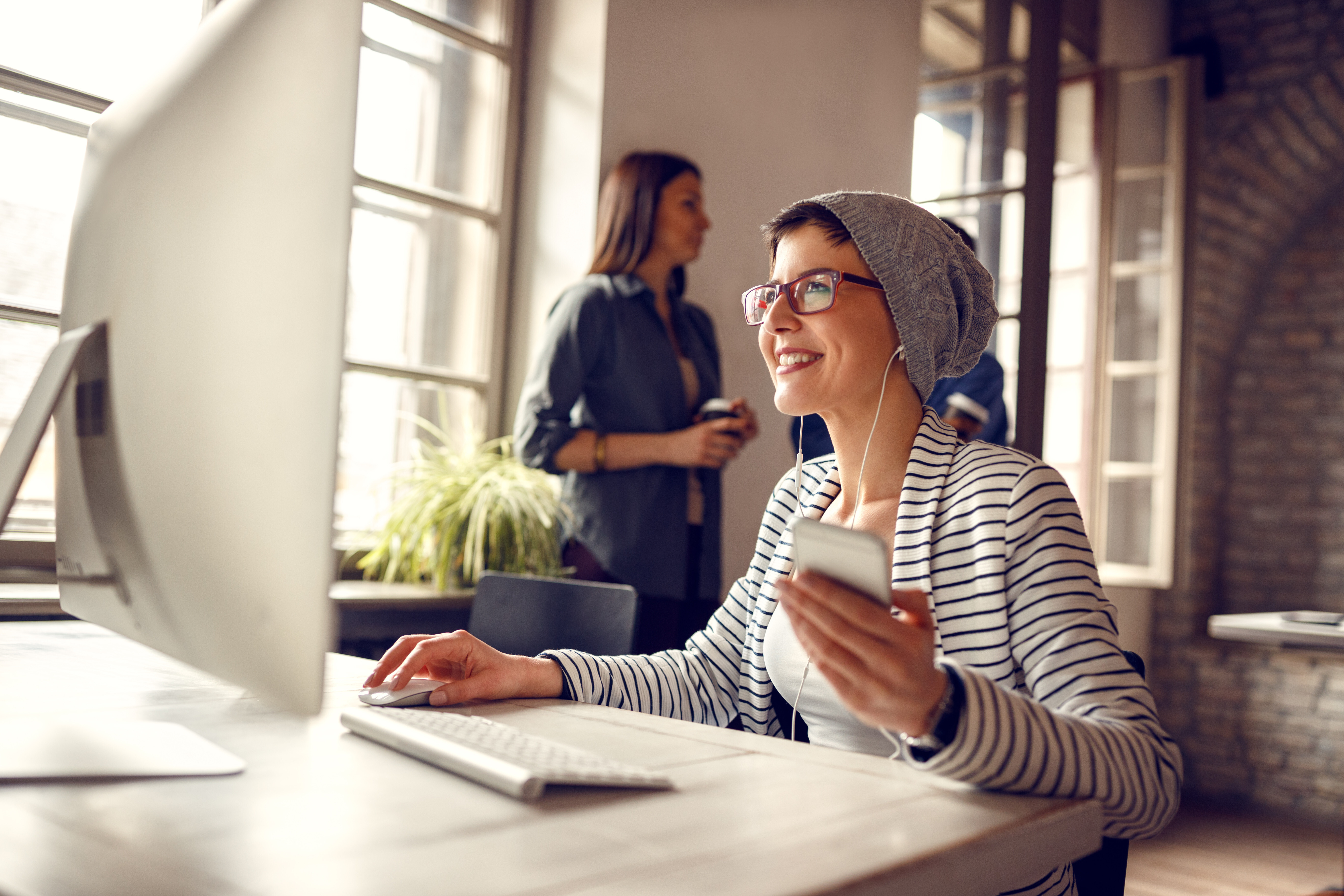 Woman in a hat smiling at her computer, demonstrating how Crowdalert simplifies security with actionable alerts