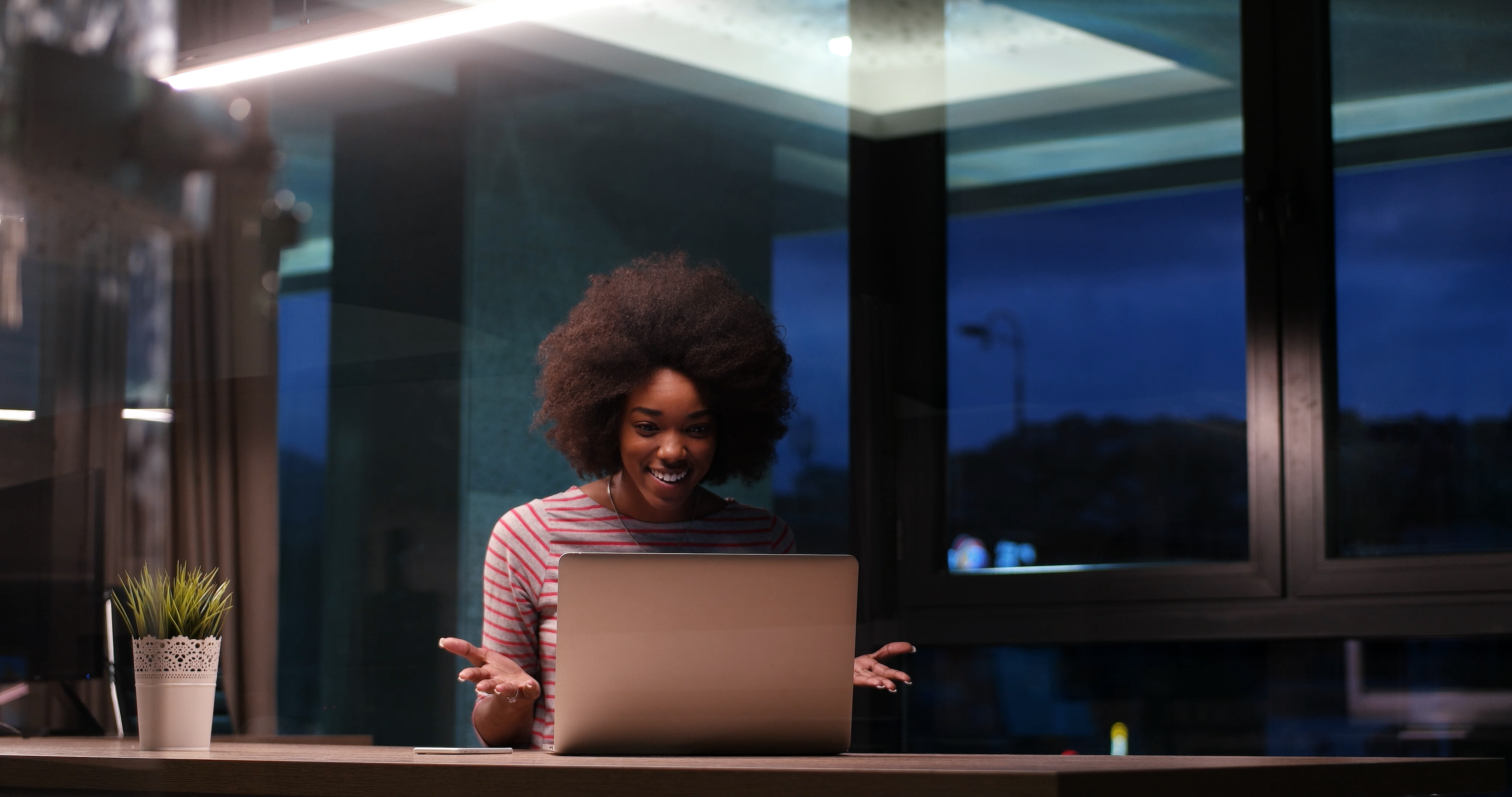 Woman smiling at her laptop, illustrating the positive impact of security tools that minimize unnecessary alerts and noise