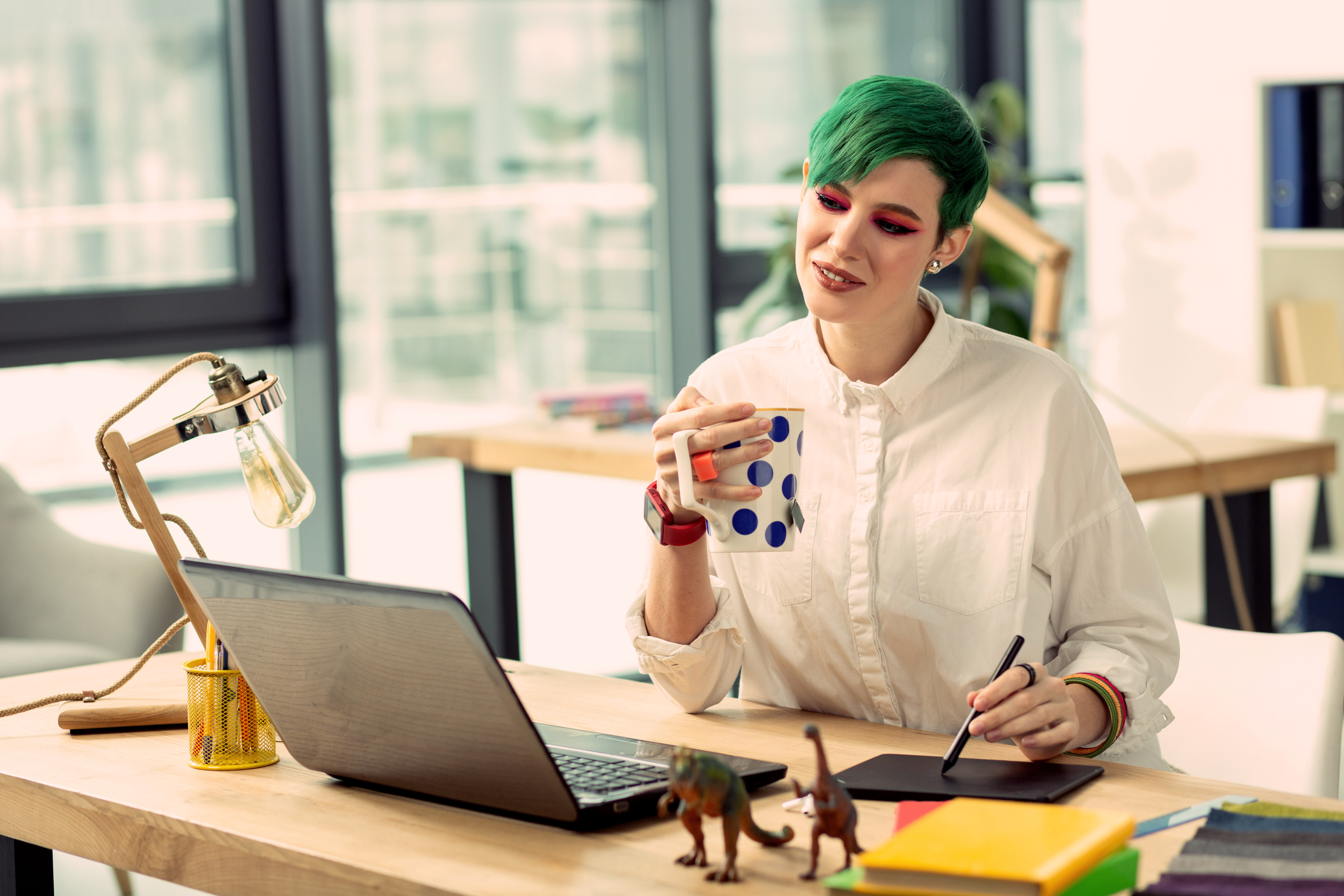 Woman with green hair smiling at her computer, demonstrating the ease of using Slack for SecOps alert management with Crowdalert